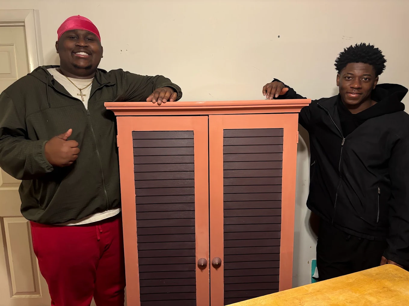 Two Big Guy Moving crew members with a painted cabinet delivered inside