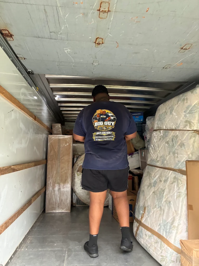 Big Guy Moving crew member loading a box truck with mattresses and boxes