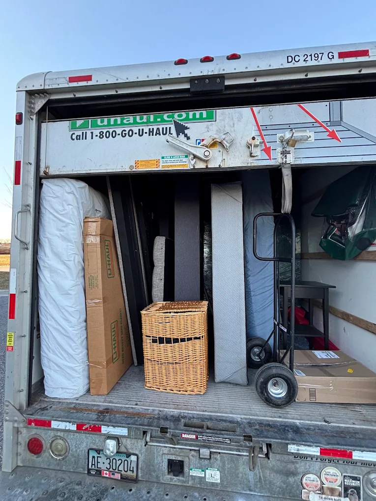 A U-Haul truck packed tight with mattresses, furniture and a hand truck