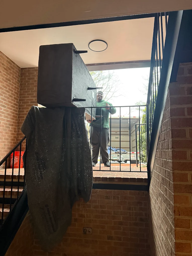 Wrapped furniture handed down a brick apartment stairwell