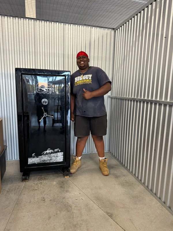 Crew member beside a gun safe delivered into a storage unit