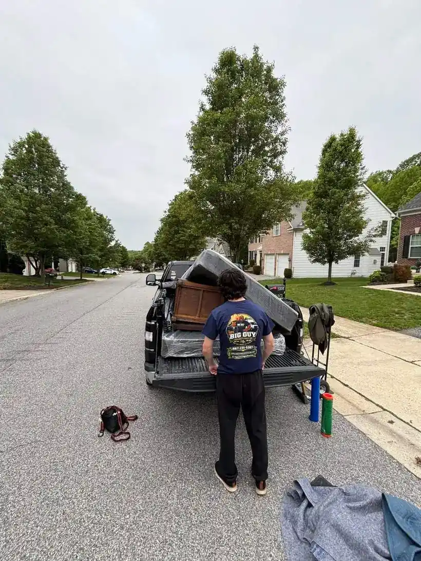 Big Guy Moving crew member loading a mattress and antique dresser onto a pickup