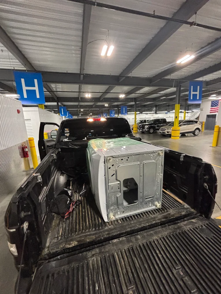 A dryer strapped into a pickup truck inside a parking garage