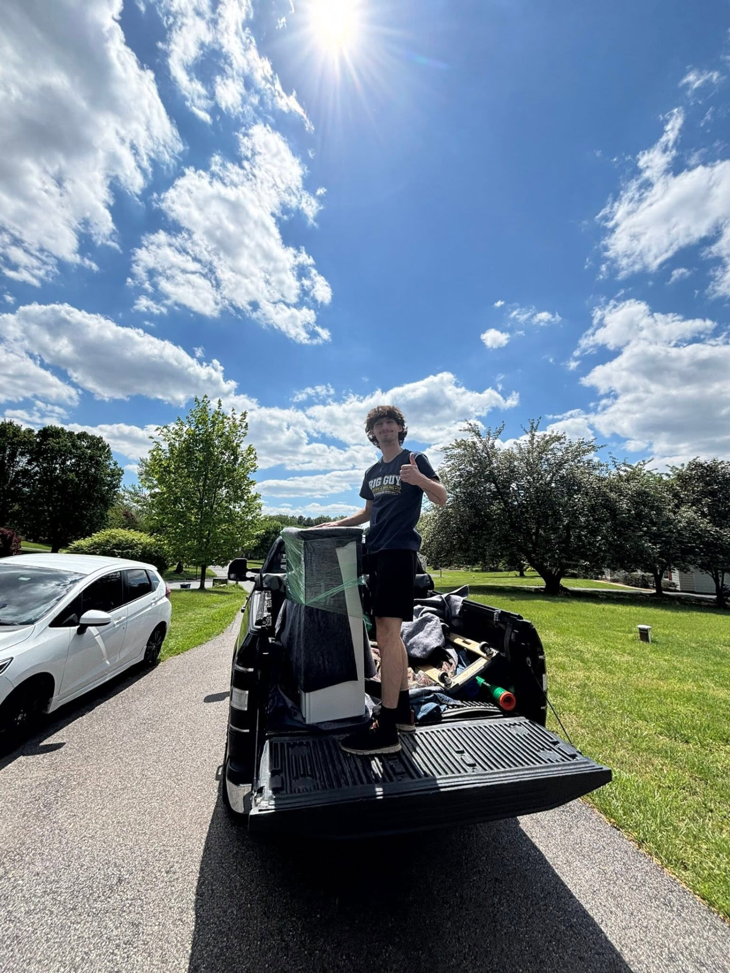 Big Guy Moving crew member giving a thumbs up on a loaded truck bed on a sunny day