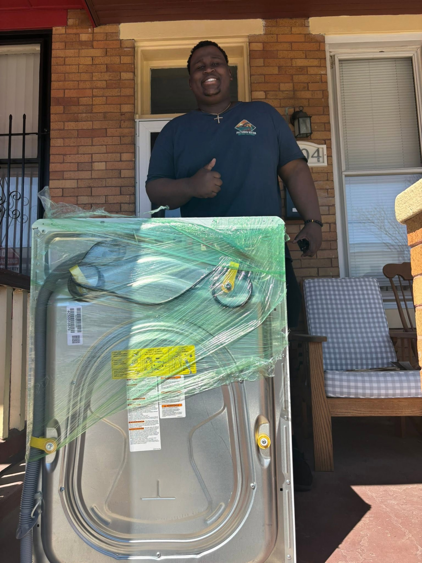 Big Guy Moving crew delivering a shrink-wrapped washer to a Baltimore rowhome porch