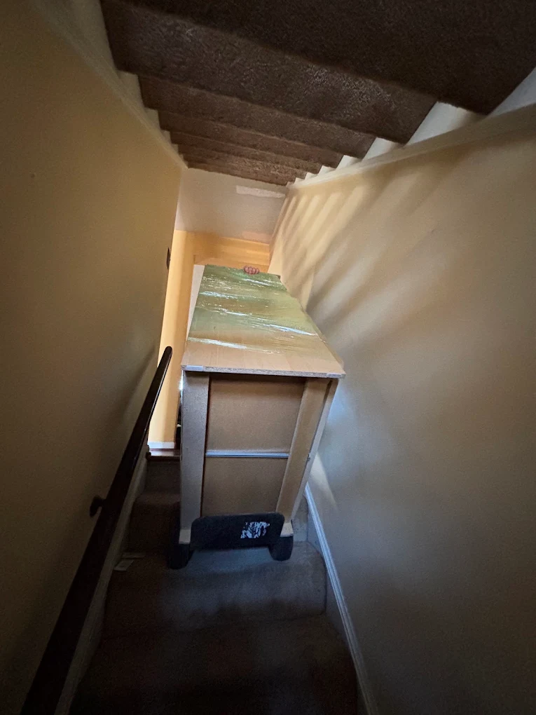 Wrapped cabinet on a stair dolly in a narrow stairwell