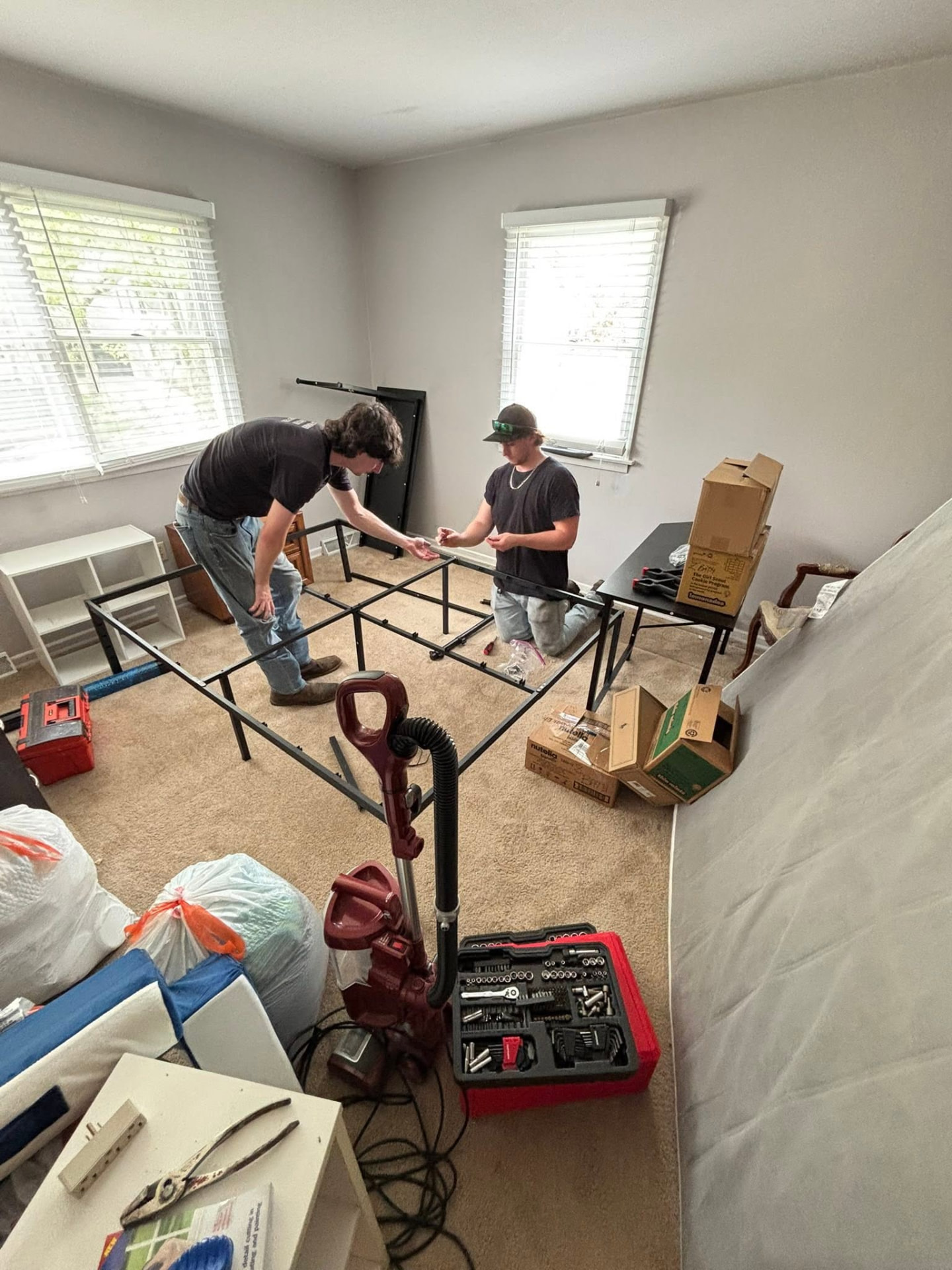 Big Guy Moving crew assembling a metal bed frame in a bedroom