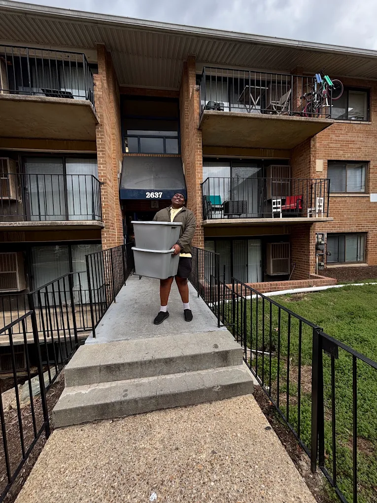 Aaron carrying stacked storage bins out of a Baltimore apartment building