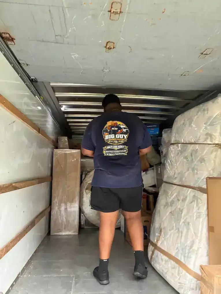 Big Guy Moving crew member loading a box truck with mattresses and boxes