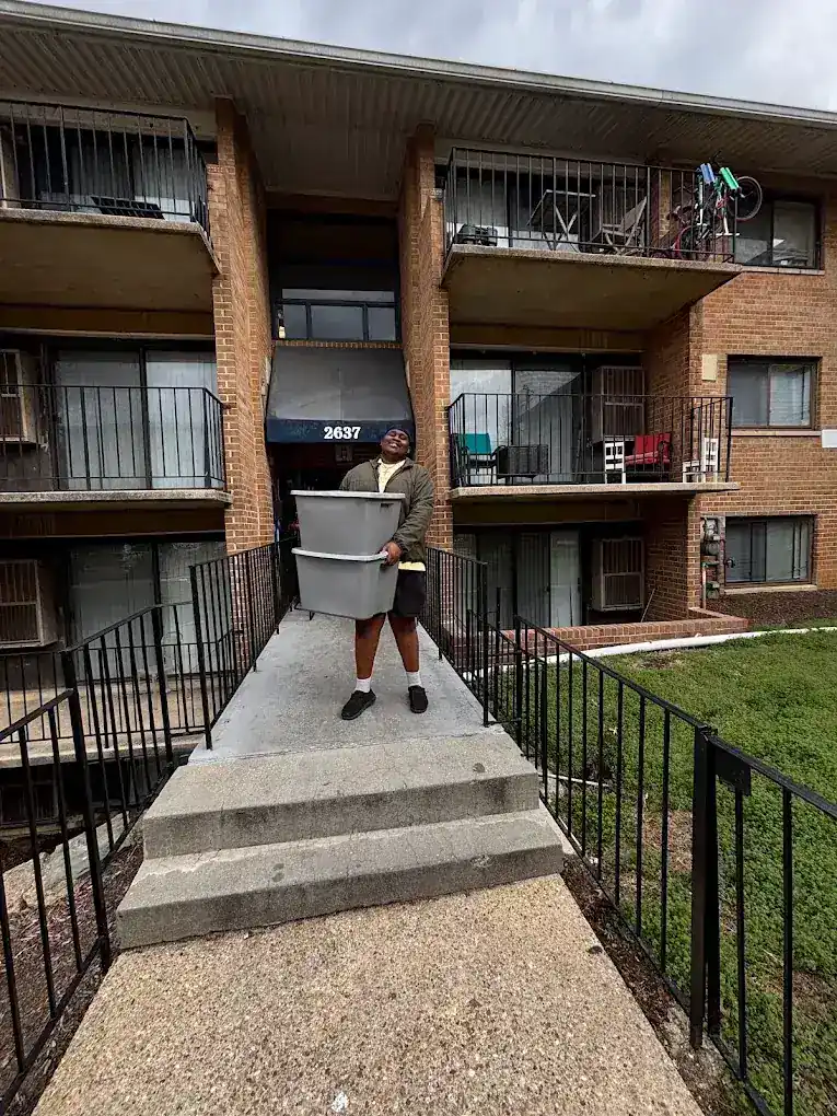 Aaron carrying stacked storage bins out of a Baltimore apartment building