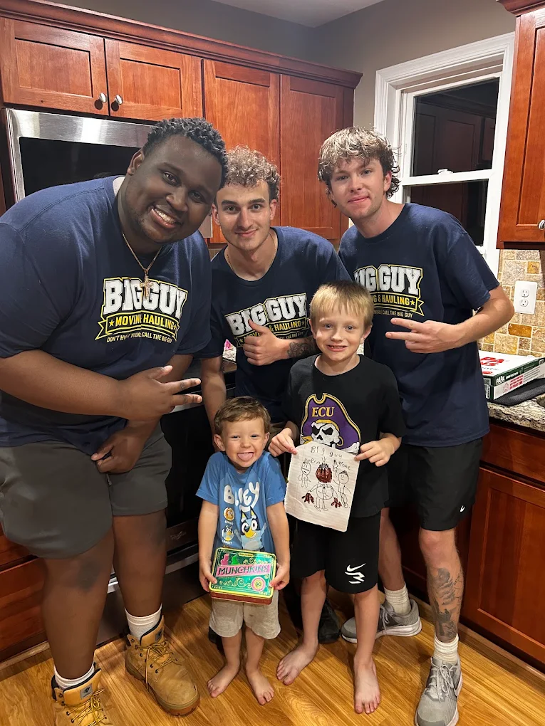 Big Guy Moving crew posing with two kids and their drawing
