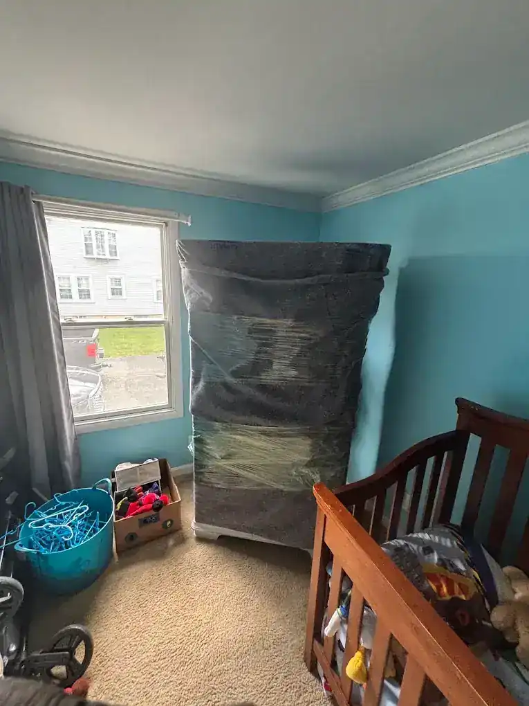 A wrapped mattress and crib mattress staged in a child's bedroom