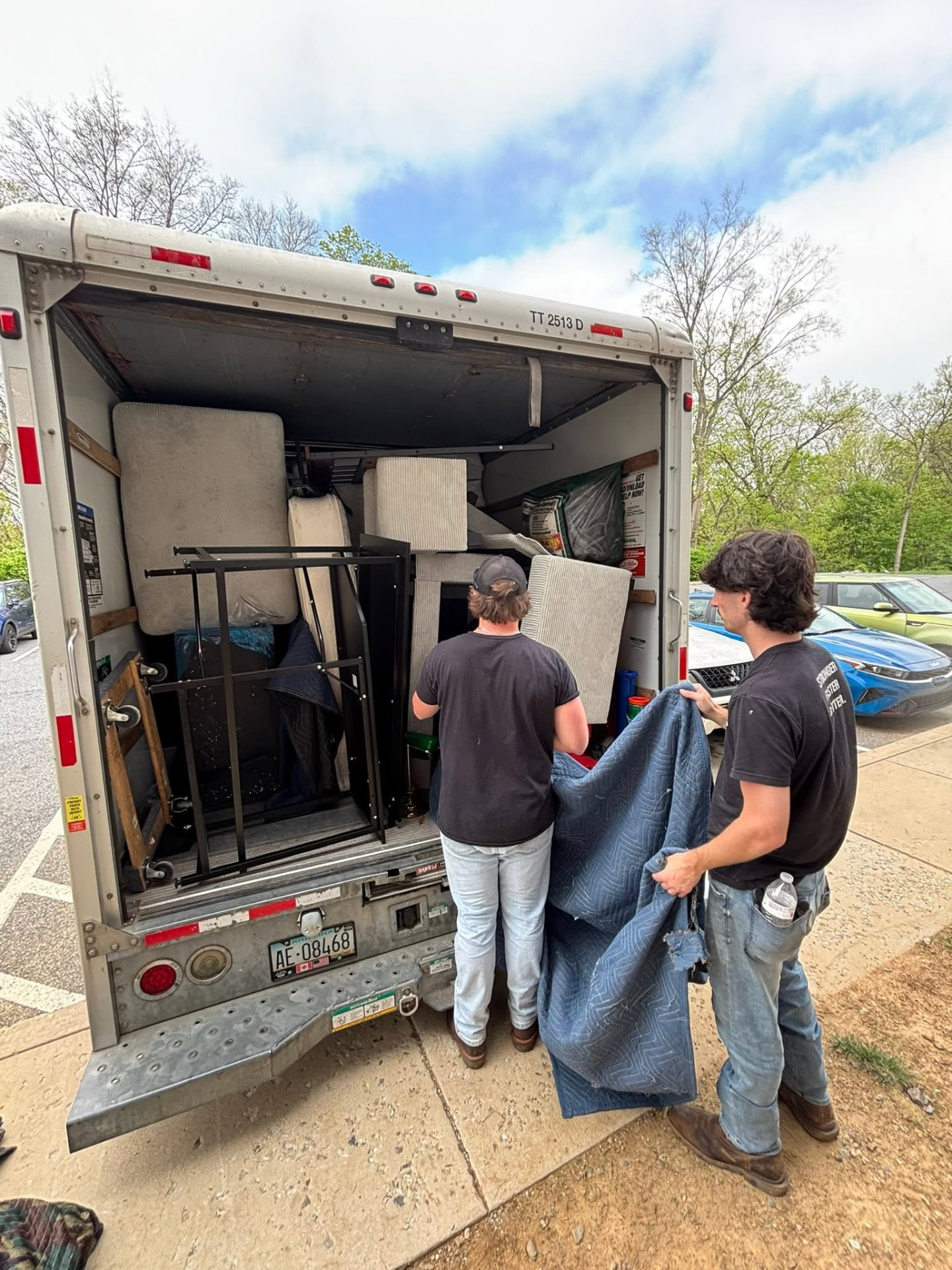 Two Big Guy movers blanket-wrapping furniture at the back of a box truck